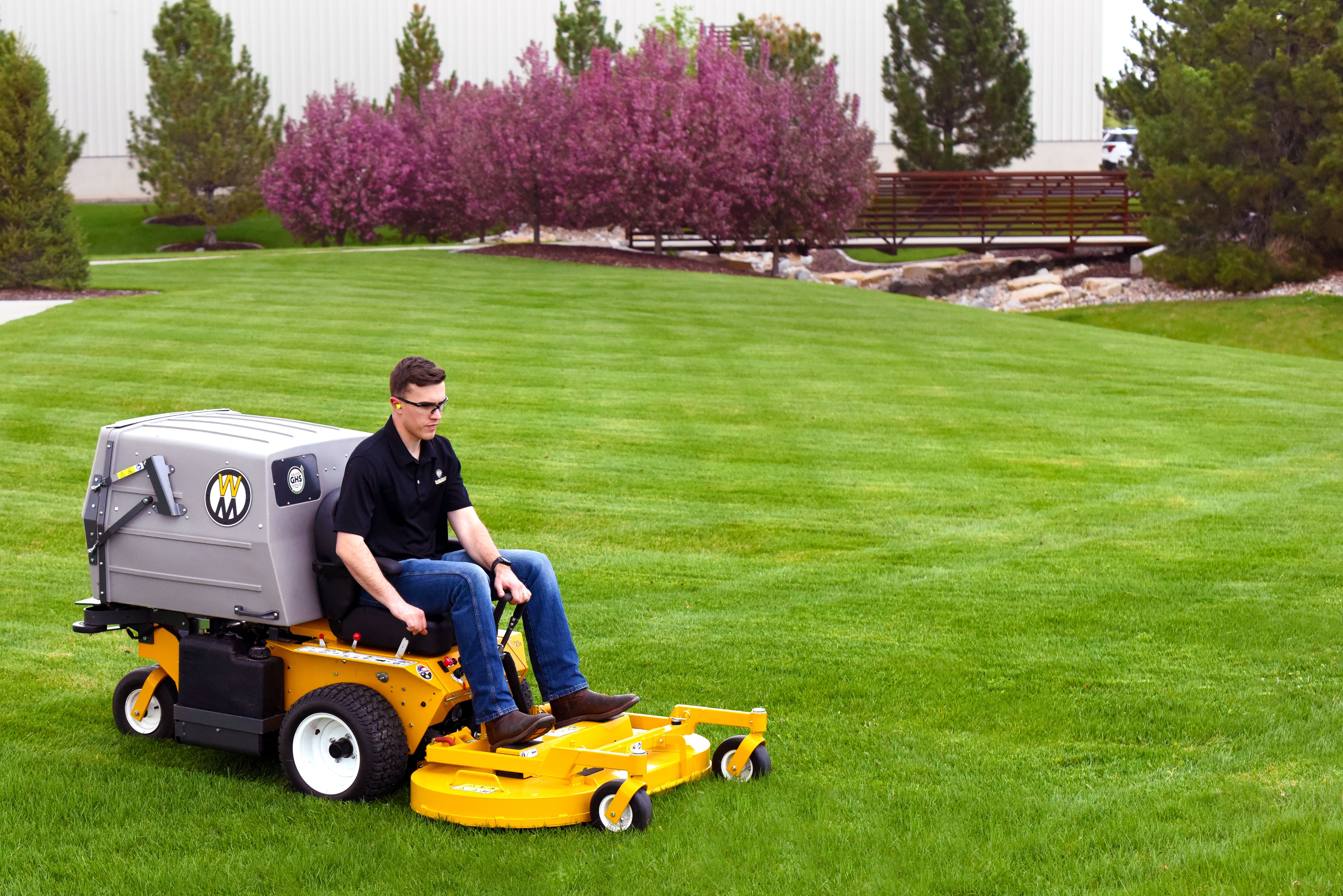 Z Force Walker C23I Mowing A Green Landscaped Lawn Beside Pink Flowering Trees